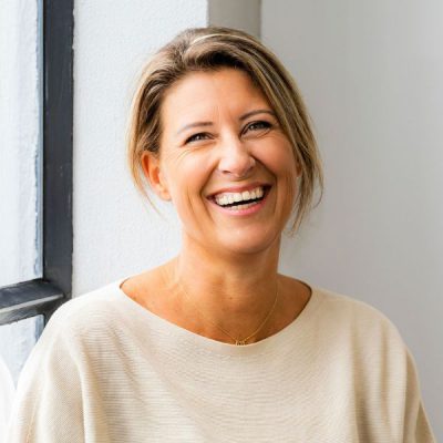 Lachende vrouw bij raam in lichte kamer, gelukkig en ontspannen, moderne lifestyle, portret, frisse uitstraling, natuurlijke look, lichtgewicht, vriendelijk, binnen, bedrijfsruimte, licht en schaduw999999.