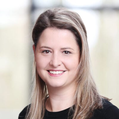 Gezichte van een lachende vrouw met lange bruin haar in een zakelijke omgeving, professioneel portret, licht en helder, moderne stijl, voor SEO over professionaliteit en vriendelijkheid.