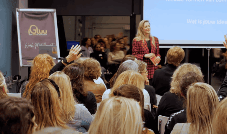 Werkende vrouw presenteert tijdens conferentie over licht en communicatie, publiek in een moderne zaal, inspirerende zakelijke sfeer, aandacht voor technologie en innovatie.