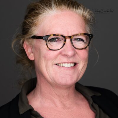 Gezicht met glimlach en bril met tortoise rand, portret van een vrouw met rood haar en lichte huid, professionele studio-omgeving.
