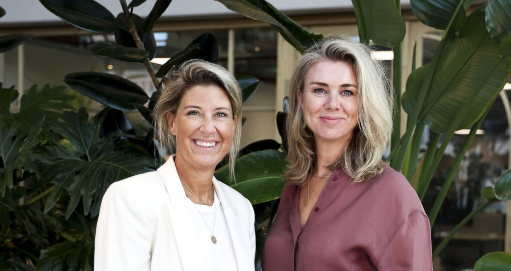 Gezellige vrouwen in een groene binnenomgeving met grote plant, focus op licht en natuurlijke sfeer, perfect voor foto's over tuin, interieur of natuur.