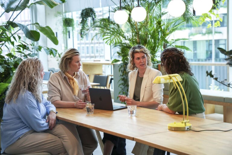 Kantoorverlichting met natuurlijke groene planten, moderne hanglampen en werkomgeving voor een aangename sfeer.