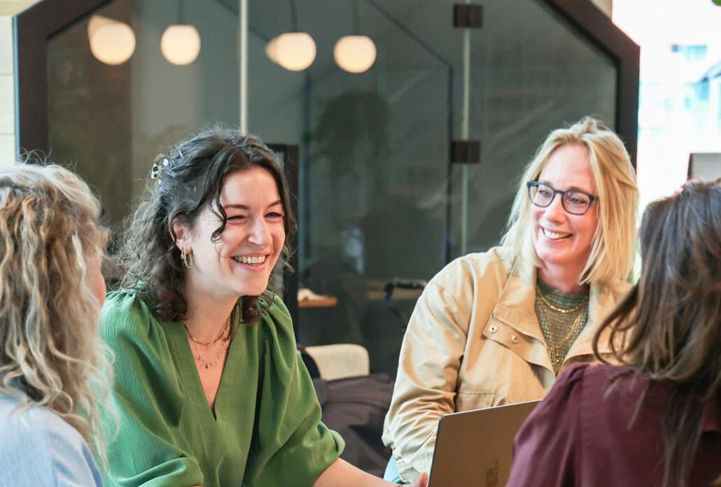Lichtverbindingen in een moderne kantoorruimte met mensen die genieten van een creatief gesprek, benadrukt de energie en innovatie in lichtontwerp.