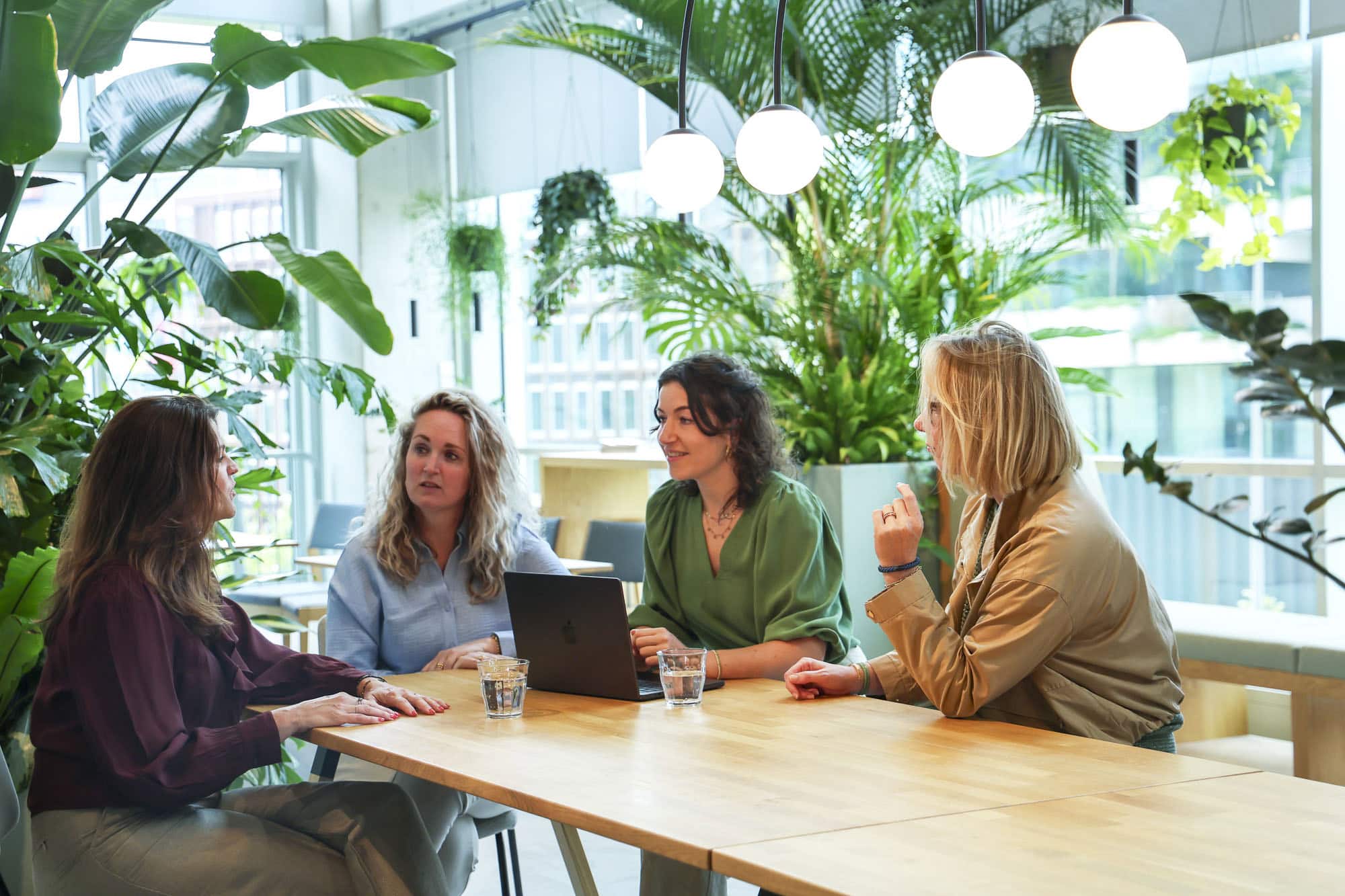 LICHT teammeeting in een modern kantoorruimte met natuurlijke planten, verlichte plafondlampen, werken aan een laptop, creatieve en inspirerende werkomgeving, gezonde binnenverlichting, groene kantoorinterieur, zakelijke bijeenkomst, duurzaam design.
