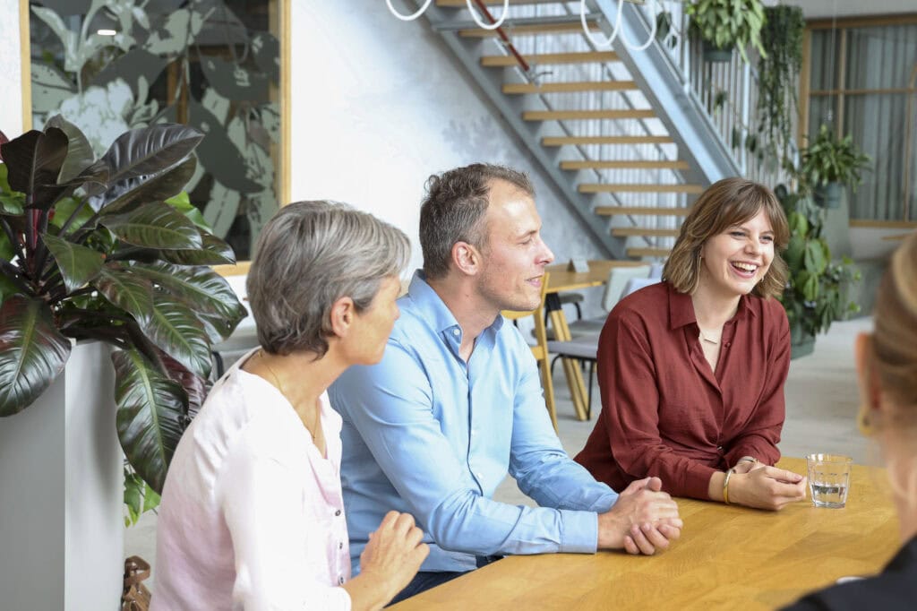 Gezellige vergadering met lachende collega's in een modern kantoor, verbeter de werkplek met goede verlichting en natuurlijke lichtinval voor meer creativiteit en welbevinden.