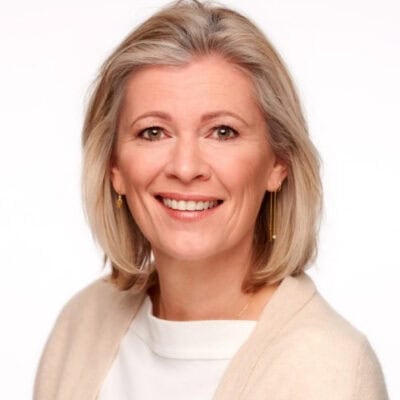 Lichtt, portretfoto van een glimlachende vrouw met blonde haar en witte top, professionele uitstraling, voor branding en communicatie, licht en vriendelijk sfeer, moderne uitstraling, zakelijke look, vrouwelijk, stijlvolle kleding, lifestyle, online professionals, persoonlijke ontwikkeling.