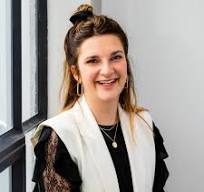 Stralende vrouw die lachend poseren bij raam met natuurlijke lichtinval, modern interieur, casual stijl.