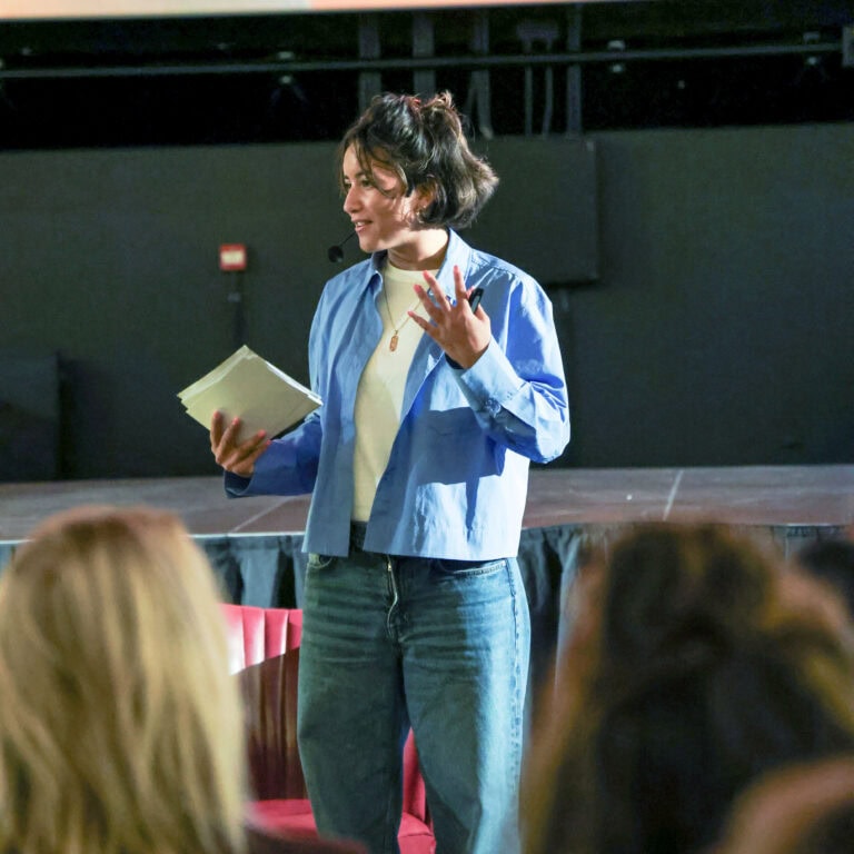 Presentatie over lichttechnologie door een vrouw in een auditorium, met de focus op belichting en verlichting in een professionele setting.